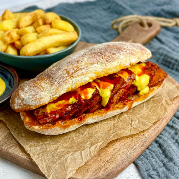 vegan Portuguese bifana on a chopping board with chips.