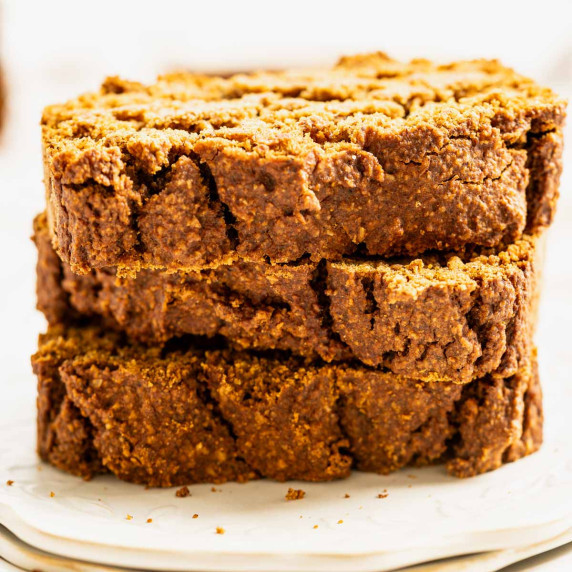 Three slices of pumpkin bread stacked on a white plate.