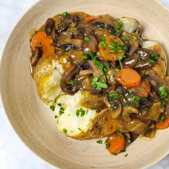 Baked potato in a wooden bowl full of vegan stew.