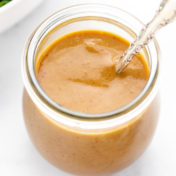 Spicy brown mustard in a glass jar with a spoon.