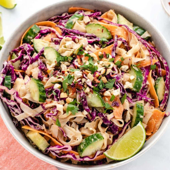 Vegan peanut noodles with carrots, carrots, and red cabbage in a bowl.