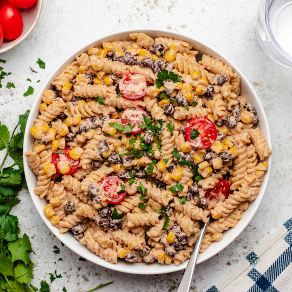 Vegan taco pasta salad with black beans, corn, and cherry tomatoes in a bowl.