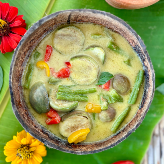 Vegetarian Thai green curry with vegetables served in a coconut shell.