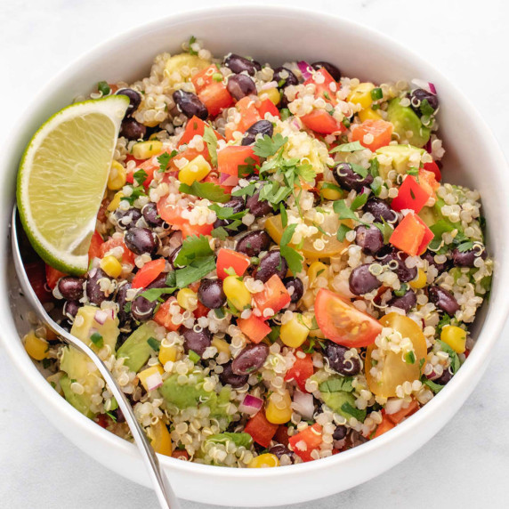 Zesty quinoa salad in a bowl with a lime wedge.